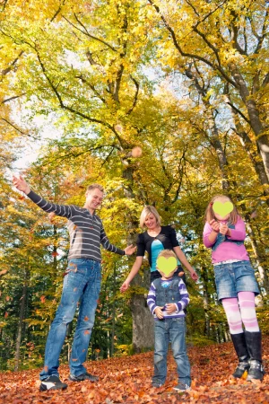 Familienfoto einer glücklichen Familie beim Fotoshooting mit einem Fotograf draussen im herbstlichen Wald