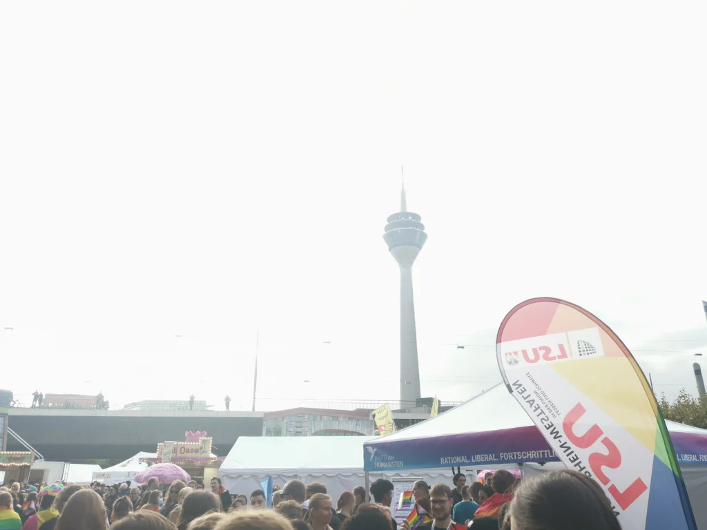 Rheinturm Düsseldorf umgeben vom hellen Himmel und der Pavillion der Partei der Humanisten beim CSD Düsseldorf 2021