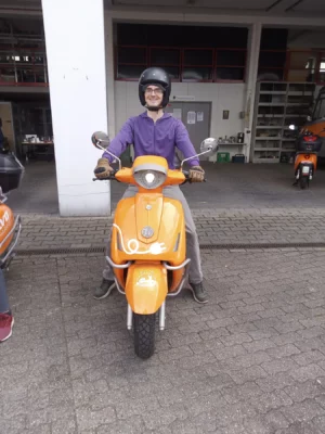 Mann sitzt grinsend auf einem elektro-angetriebenen Sharing Moped der Firma evo-sharing