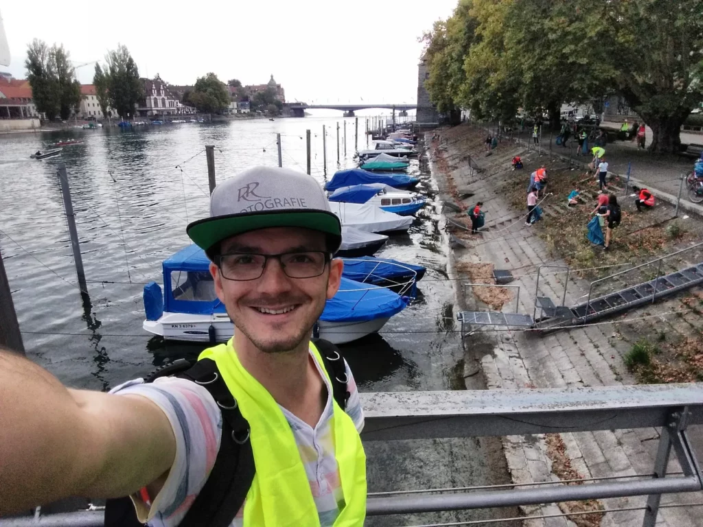 Mann macht Selfie am Wasser des Rheins in Konstanz am Bodensee während dem Event Clean Up Day Rhein.