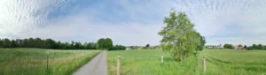 Panoramafoto von einer Landschaft beim Ort Essen-Haarzopf im Mai. Mit Straße, grüner Wiese, und blauem Himmel