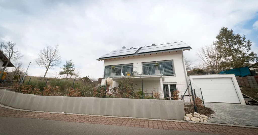 3 stöckiges Haus mit Solar auf dem Dach. Garage daneben und Vorgarten