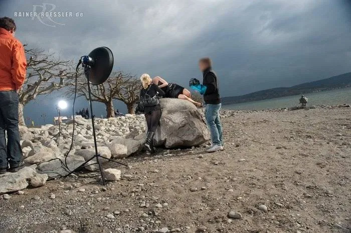 Menschen draußen in der Natur am Wasser während einem Fotoshooting. Dunkle Wolken.