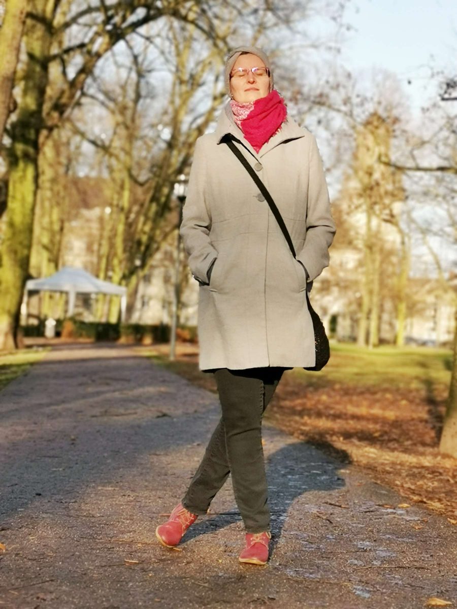 Hübsche Frau steht an einem sonnigen Wintertag im Dezember 2019 im Krefelder Stadtgarten und lässt sich von Fotografen Rainer Rössler mit seinem Smartphone ablichten.